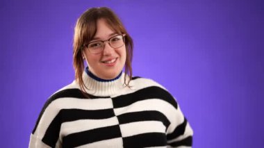 20 'li yaşlarda, kendini beğenmiş genç bir kadının portresi. Mor arka planda bilerek izole edilmiş parmağını gösteriyor.