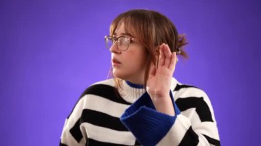 Kafkasyalı 20 'li yaşlardaki hippi kadın portresi mor arka plan stüdyosunda izole edilmiş ve fotokopi alanı olan gizli şarkıları dinlemek için kulaklarını tıkıyor.