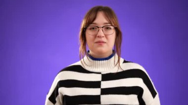 20 'li yaşlarda genç bir kadının portresi kameraya bakıyor alkışlıyor alkışlıyor olumlu duygu ve destek gösteriyor mor arka planda izole edilmiş iyi bir performansa.