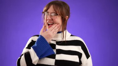 Stüdyoda mor arka planda izole edilmiş diş ağrısı sorunu olan 20 'li yaşlarda genç bir kadının portresi.