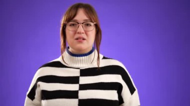 Mor arka plan stüdyosunda yirmili yaşlarda yalnız poz veren yorgun ve bitkin bir baş ağrısı migreni portresi. Ellerini baş masajına koy