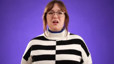 Kızgın, korkmuş 20 'li yaşlarda genç bir kadın ellerini başının üstüne koyup bağırıyor ve neden mor arka plan stüdyosunda soyutlandığımı soruyor. Halk yaşam tarzı konsepti.