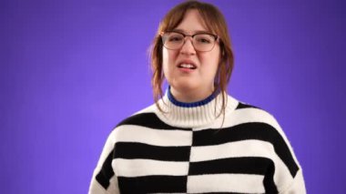 20 'li yaşlarda güzel esmer bir kadının portresi mor arka plan stüdyosunda izole bir şekilde poz veriyor, bağırıyor, kükreyerek çığlık atıyor..