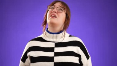 Kızgın, korkmuş 20 'li yaşlarda genç bir kadın ellerini başının üstüne koyup bağırıyor ve neden mor arka plan stüdyosunda soyutlandığımı soruyor. Halk yaşam tarzı konsepti.