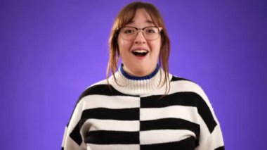 Heyecanlı 20 'li yaşlarda genç bir kadının portresi büyük başarı bekliyor, kazanan, mor arka planda izole edilmiş..