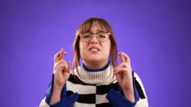 Umut dolu 20 'li yaşlarda genç bir kadının portresi büyük başarı bekliyor, kazanan, mor arka planda izole edilmiş..