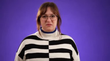 20 'li yaşlarda güzel, esmer bir kadının portresi mor arka plan stüdyosunda izole bir şekilde poz veriyor, yavaş çekimde kükreyerek bağırıyor, çığlık atıyordu..