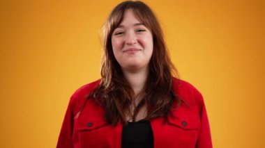 Genç, mutlu, kahverengi saçlı, kırmızı ceketli güzel bir kadın. Sarı arka planda izole edilmiş, fotokopi alanı ağır çekimde.