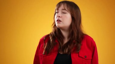 Beyaz kadın portresi, 20 'li yaşlarda sarı arka plan stüdyosunda kopyalanmış gizli şarkıları dinlemek için el ele tutuşuyor.