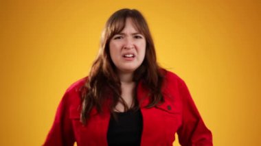 20 'li yaşlarda güzel esmer bir kadının portresi sarı arka plandaki stüdyoda izole edilmiş poz veriyor, kükreyerek bağırıyor, çığlık atıyor..