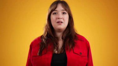 Heyecanlı, şaşırmış, gülümseyen, 20 'li yaşlarda genç, güzel bir hippi kadının portresi sarı arka plan stüdyosunda izole edilmiş.