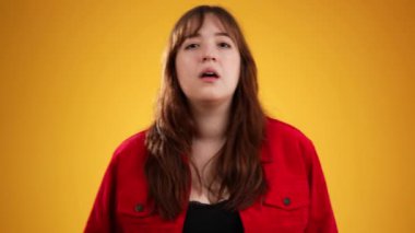 Kameraya parmak çerçevesinden bakan kadının portresi sarı arkaplanda kopya alanı ile izole edilmiş.