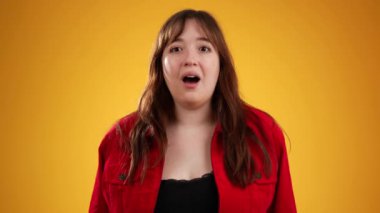 Heyecanlı, şaşırmış, gülümseyen, 20 'li yaşlarda genç, güzel bir hippi kadının portresi sarı arka plan stüdyosunda izole edilmiş.