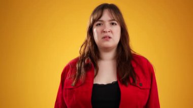 20 'li yaşlarda güzel esmer bir kadının portresi sarı arka plandaki stüdyoda izole edilmiş poz veriyor, kükreyerek bağırıyor, çığlık atıyor..