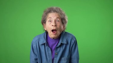 Heyecanlı, başarılı, yaşlı, buruşuk derili, yeşil ekran arka plan stüdyosunda izole edilmiş gri saçlı yaşlı bir kadının portresi.