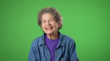 Gülümseyen yaşlı bir kadının portresi. Cildi kırış kırış ve saçları yeşil perde arkasında..