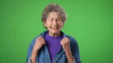 Kızgın, korkmuş, yaşlı, buruşuk derili, kır saçlı yaşlı bir kadın ellerini uzattı ve neden yeşil ekran arka plan stüdyosunda soyutlandığımı sordu. Halk yaşam tarzı konsepti.