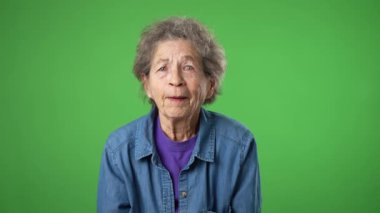 Yaşlı, yaşlı, buruşuk derili ve gri saçlı yaşlı bir kadının portresi stüdyodaki yeşil ekran arka planında büyük başarı elde ediyor. İnsanlar samimi duygular, yaşam tarzı konsepti.