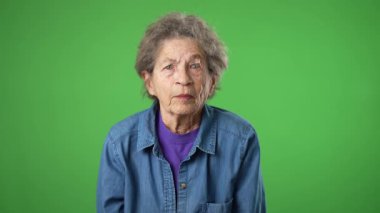 Öfkeli ümitsizliğin portresi, yeşil ekranda izole edilmiş kırışık derili ve gri saçlı yaşlı yaşlı bir kadının portresini altüst ediyor..
