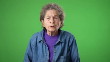 Hoşnutsuz, sinirli, sinirli, yaşlı, yaşlı, buruşuk derili, gri saçlı, gözleri kapalı, kulakları kapalı yaşlı kadın yeşil ekran arka plan stüdyo resminde izole edilmiş çığlıkları dinlemek istemiyor.