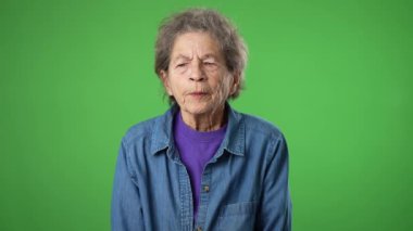 Düşünce portresi, akıllı şaşkın yaşlı düşünceli, yaşlı, buruşuk derili, gri saçlı yaşlı kadın yeşil ekran arka plan stüdyosunda parmak kaldıran fikirlerle düşünüyor.