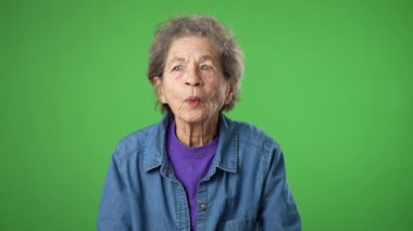 Mutlu yaşlı yaşlı kadın portresi, buruşuk derili, gri saçlı, gülümseyen ve arkadaşını arayan yeşil perde arkasında yalnız poz veren biriyle tanış..