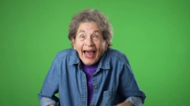 Mutlu yaşlı yaşlı kadın portresi, buruşuk derili, gri saçlı, gülümseyen, çığlık atan, bağıran, elleri ağızda davet eden yeşil ekran arka planında yaşayan,.