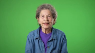 Gülümseyen mutlu yaşlı yaşlı kadın portresi. Buruşuk derili ve gri saçlı yaşlı kadın. Yeşil ekran arka planında izole edilmiş, kopyalama alanı olan iki başparmak veriyor..