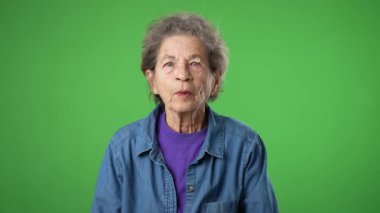 Heyecanlı, şaşırmış yaşlı kadının portresi. Yaşlı, yaşlı, buruşuk tenli, gri saçlı, yeşil ekran arka plan stüdyosunda izole edilmiş bir şekilde gülümsüyor.