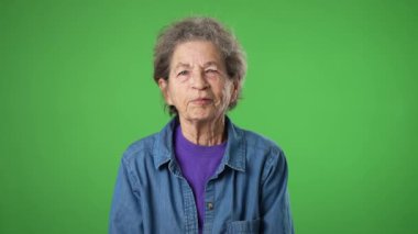 Mutlu, gülümseyen, yaşlı, yaşlı ve yaşlı bir kadının portresi. Kırışık derisi ve yeşil perde arkasında gri saçları var. Samimi duygular