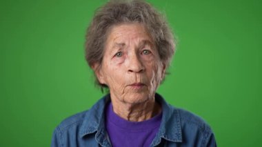 Yakın çekim yavaş çekim mutlu gülümseyen yaşlı bir kadın portresi kırışık cilt ve yeşil ekran arka planında gri saçlar.