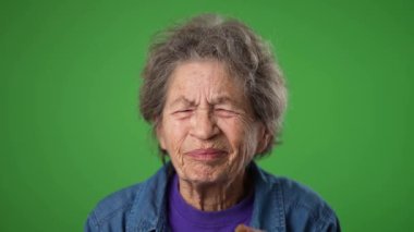 Yaşlı bunalımlı yaşlı kadın 80 'li yaşlarda. Migren ağrısı var. Yeşil ekran arka plan stüdyosunda yalnız poz veriyor. İnsanların yaşam tarzı kavramına yakın olmak. Yüzünü dön.