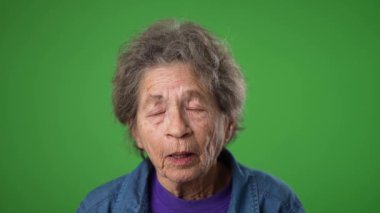 Yaşlı bunalımlı yaşlı kadın 80 'li yaşlarda. Migren ağrısı var. Yeşil ekran arka plan stüdyosunda yalnız poz veriyor. İnsanların yaşam tarzı kavramına yakın olmak. Yüzünü dön.