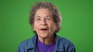 Yakın çekim yavaş çekim mutlu gülümseyen yaşlı bir kadın portresi kırışık cilt ve yeşil ekran arka planında gri saçlar.