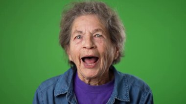 Mutlu gülümsemenin yavaş çekim portresi heyecanlı yaşlı kadın başını sallıyor evet, kırışık cilt ve yeşil ekran arka planında gri saçlar.