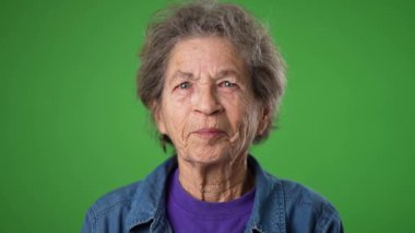 Yakın çekim, heyecanlı kazananın portresi. Yaşlı, gülümseyen yaşlı bir kadın. Kırış kırış bir ten ve yeşil perde arkasında gri saçlar..