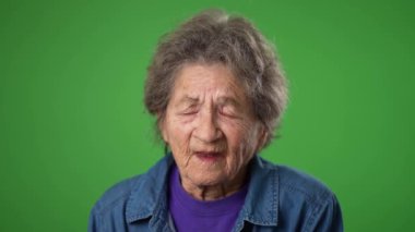 Yaşlı, yorgun, dişsiz, olgun, yaşlı bir kadının migren ağrısı olan portresi yeşil ekran arka plan stüdyosunda izole edilmiş. İnsanların yaşam tarzı kavramına yakın olmak. Yüzünü dön.