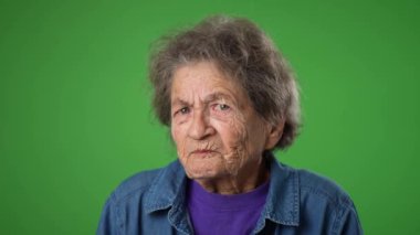 Ağır çekimde dişleri dökülmüş, ümitsizlikten sinirlenmiş yaşlı bir kadının hava portresiyle kaldırılmış elleri üzgün. 80 'li yaşlarda, yeşil ekran arkasında izole edilmiş..