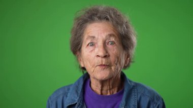 Kapalı çekimde, yaşlı, dişsiz yaşlı bir kadının portresi. Kırışık ciltli, gri saçlı, kolları havada. Başarılı, yeşil ekran arka planında izole edilmiş..