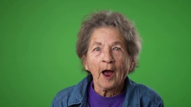 Dişsiz, yaşlı, buruşuk derili ve gri saçlı yaşlı bir kadının yeşil ekranda izole edilmiş başarılı kazananı ile mutlu olan yavaş çekimde portresi. Duygular konsepti
