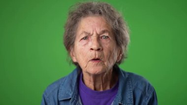 Gülümseyen, dişsiz, buruşuk derili ve gri saçlı mutlu büyükannenin komik yakın çekim portresi yeşil ekran arka plan stüdyosunda izole edilmiş sırları dinlemek için el ele veriyor.