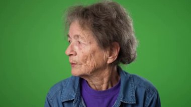 Gülümseyen, dişsiz, buruşuk derili ve gri saçlı mutlu büyükannenin komik yakın çekim portresi yeşil ekran arka plan stüdyosunda izole edilmiş sırları dinlemek için el ele veriyor.