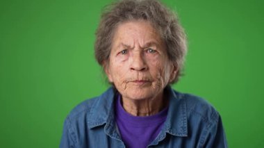 Mutsuz, sinirli, üzgün, dişsiz, yaşlı, yaşlı, buruşuk derili, gri saçlı, kulakları kapalı yaşlı bir kadın.