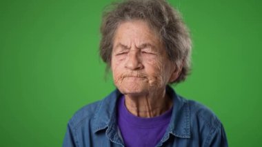 Düşünceli, düşünceli, yaşlı, dişsiz, yeşil ekran arka planında parmakları olan harika fikirli kadının aşırı yakın çekimi..