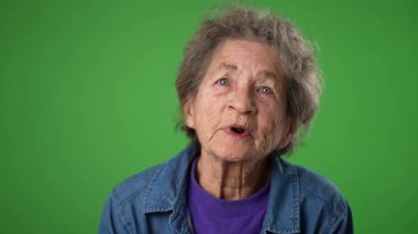 Kapalı çekimde, yeşil ekranda konuşan buruşuk derili, mutlu, dişsiz yaşlı bir kadının portresi..