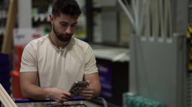 Ahşap kereste bölgesindeki hırdavatçı dükkanında elinde alışveriş arabası olan bir adamın fotoğrafı..