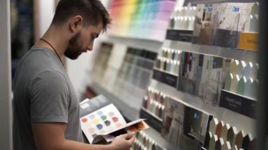 Hırdavatçıda broşür okuyan adam sayfaları çeviriyor. Ev yenileme deneyimini kavramsal olarak kabul et..