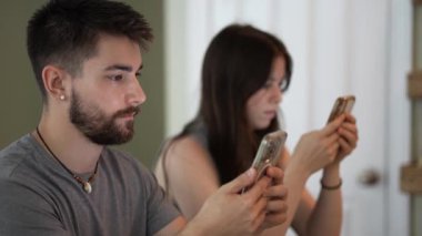 Genç çiftlerin mesajlaşmaları, araştırmaları, yazmaları, telefonları üzerinde çalışmaları, konuşmaları ve evlerindeki bir tezgahta mesajlaşmaları....