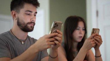 Genç mutlu çiftin telefonlarıyla kafede mesajlaşmaları, araştırmaları, daktilo etmeleri ve çalışmalarının aşırı yakınlaşması..