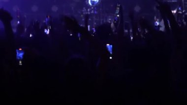 Bir konser ya da festival partisinde dans eden tanınmayan hayranların dikey videosu. Konser kalabalığının siluetleri yanıp sönen sahne ışıkları önünde